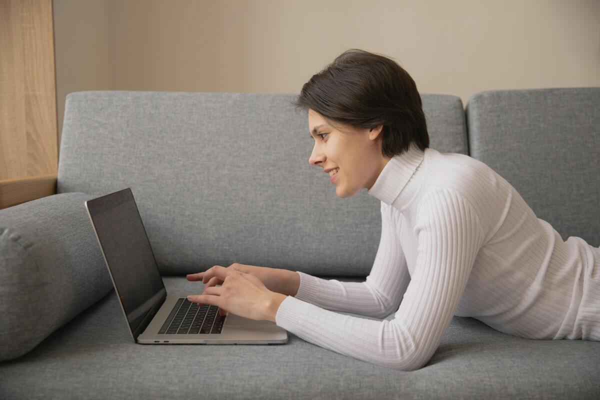 woman lying on a sofa using a laptop, CV structure