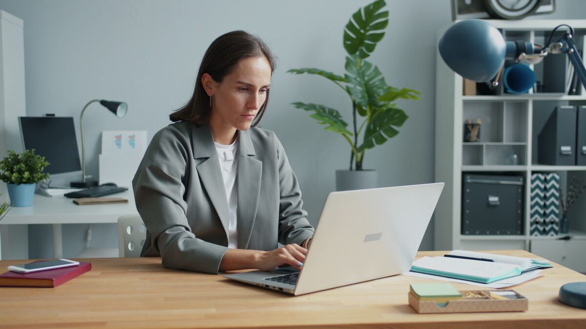 businesswoman focused on laptop in modern home office setting, cv writing service cost